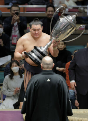 L’ôzeki Hoshoryu (face à la caméra) reçoit le trophée du championnat des mains du chef de l'Association japonaise de sumo Hakkaku après avoir remporté le Hatsu Bashô le 26 janvier 2025, au Ryogôku Kokugikan de Tokyo. (Kyodo)