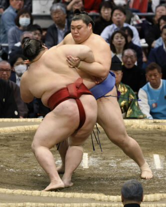 L’ôzeki Onosato (face caméra) et Takanosho s'affrontent lors de la sixième journée du Haru Bashô à l'Edion Arena d'Osaka, le 14 mars 2025. (Kyodo)